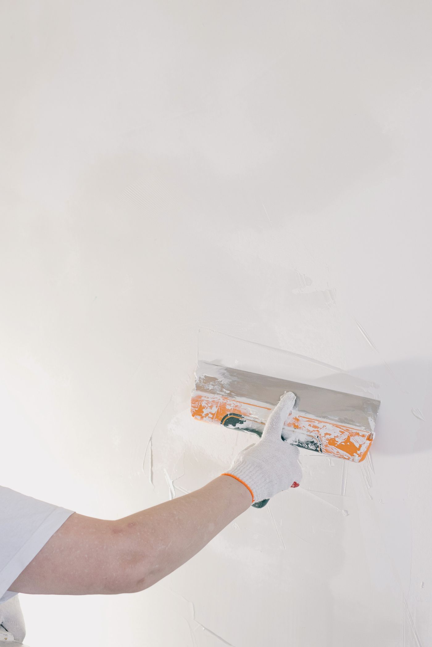 Stock inspiration: a gloved hand smoothing material onto an interior wall.